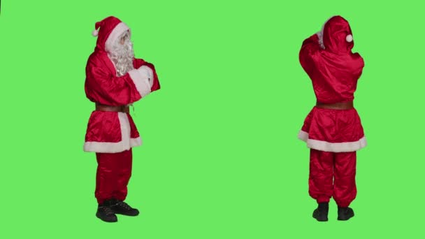 インパクトのあるサンタクロースは腕時計を観察し フルボディグリーン上に立っている間に時間厳守しようとします クリスマスの精神を広める白ひげのセントニックキャラクター — ストック動画