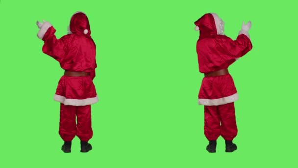 クリスマスホリデーシーズン中にマーケティング広告を行う聖ニックは フルボディグリーン背景に広告を作成します 12月のスタジオで両側を指すコスチュームのサンタ イベント — ストック動画