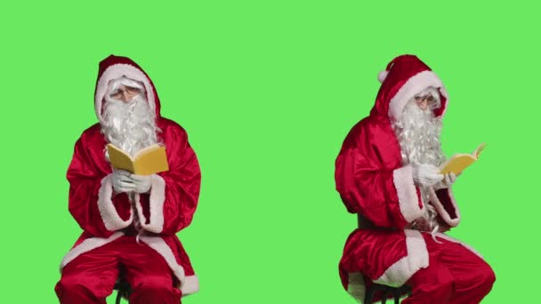 圣诞老人坐在椅子上看书 穿着节日红色服装的男人在绿屏背景下看书 圣诞老人喜欢童话故事 — 图库视频影像