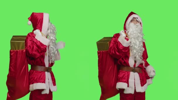サンタクロースのコスプレは グリーンスクリーンバックドロップに対するマーケティング広告を示し 主人公と冬のホリデーシーズンを宣伝するギフトバッグをポーズします 父クリスマス赤い衣装 — ストック動画