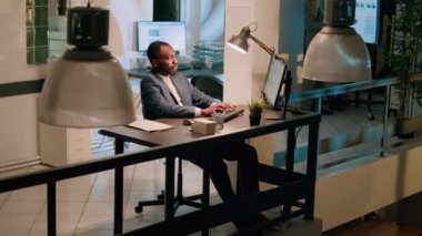 Afro-Amerikan muhasebecilerin masa başında oturup muhasebe rakamlarına bakarken, gece vardiyası sırasında bilgisayara veri yüklerken. Son teslim tarihinden önce titiz iş ekibi görevleri çözüyor
