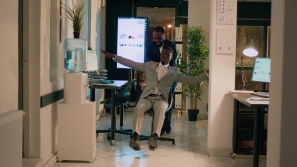 Dikkatsiz Meslektaşıyla Şakalaşan Ofis Koridorunda Sandalyesini Iten Oyuncu Bir Işçi — Stok video