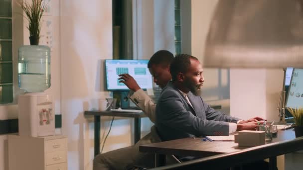 アフリカ系アメリカ人の従業員は 夜勤中に仕事を楽しみ 机の椅子を使って同僚にぶつかりました 友人はオフィスで一晩滞在中に退屈を避けるために互いにレース — ストック動画