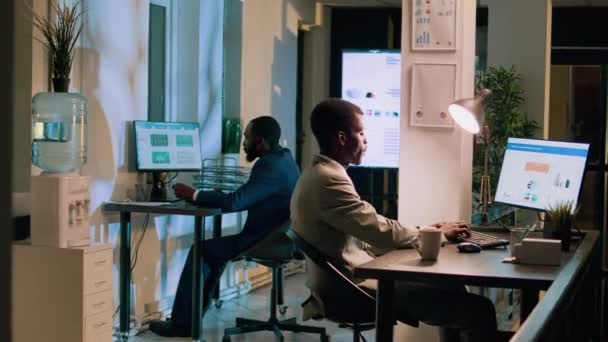 与同事一起上夜班的快乐的非洲裔美国员工的画像 工作空间中的同事们在截止日期前一夜间为团队项目做计算机任务 — 图库视频影像