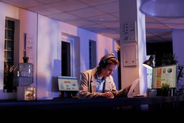 Neşeli bir şirket çalışanı müzik dinlerken finansal büyüme raporunu analiz ediyor, yatırım stratejisinde fazla mesai yapıyor. Pozitif girişimci şarkı söylüyor ve tatilde eğleniyor.