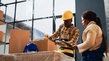 İşçiler, stok taşımacılığı için paketler hazırlıyor, depo aletleri ve konteynırlarla çalışıyorlar. Genç çalışanlar karton kutular ve perakende ürünleri kullanıyor. El kamerasıyla..