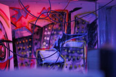 Parlak neon ışıklarıyla aydınlatılan dağınık duvarlar ve sprey boyayla kaplanmış çökmüş bir yapı. Çöpleri ve floresan mor ışıkları olan terk edilmiş eski bir bina..