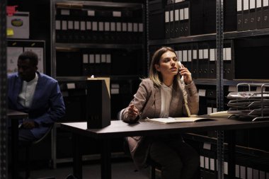 Yönetici, iş adamıyla uzaktan konuşuyor. Muhasebe raporlama odasında fazla mesai yapıyor. İdari dosyaları düzenleyen, yönetim araştırması arayan güvenilir depo çalışanı