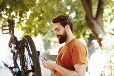 Spor Kafkasyalı bir adam bisikletiyle dışarıda yıllık yaz bakımını yapıyor. Modern bisikleti korumak ve tamir etmek için profesyonel aletlerle çalışan atletik erkek bisikletçi.