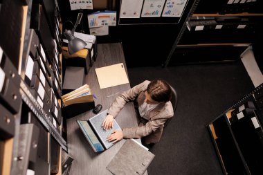 Sekreterin dizüstü bilgisayarda idari rapor yazması arşiv odasında bürokrasi kayıtlarını analiz etmesi. İş kadını gece geç saatlere kadar yönetim sisteminde çalışıyor. Depolama kavramı