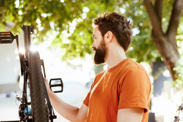 详细的图像展示了年轻活跃的高加索人在自家院子里仔细检查现代自行车的情景 骑自行车的矮胖男子看到维修和保养外面的自行车部件 — 图库照片