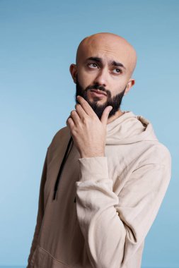 Belirsiz bir Arap, çenesini ovuşturuyor, düşünüyor ve sorgulanmış yüz ifadesiyle başka tarafa bakıyor. Genç, düşünceli, yakışıklı manken. Sıradan bir kapüşon giyiyor. Çözüm sorunu yaşıyor ve karar veriyor.