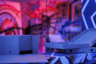 Mor ve pembe ışıklarla çökmüş yapı kaos ve bakımsızlığın karanlığında parlıyordu. Paslı duvarlarında grafiti resimleri olan terk edilmiş bir bina. Pis görünüyor. Floresan parlak ışık..