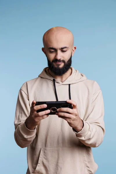レジャー活動中にスマートフォンアプリを使用し ビデオゲームをプレイするアラブ人男性 垂直モードで携帯電話を持ち オンラインでビデオを見ている若い笑顔の人 — ストック写真