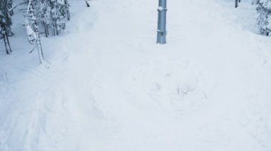 Aşağı inen kayak pistinin, dağlık tepelerdeki karla kaplı, buzlu çam ağaçlarıyla süslenmiş üst kamera görüntüsü. Uçsuz bucaksız sporlar dağların zirvesine ulaşmak için kayak kaldırma araçlarını kullanır.