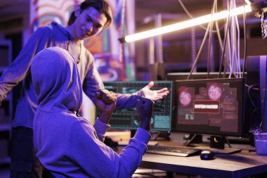 Gülümseyen suçlular veritabanını hackliyor ve başarıyla sızdıktan sonra zafer işareti gösteriyor. Mutlu genç hackerlar web sitesine sızmayı ve siber güvenlik sistemini geçmeyi kutluyor