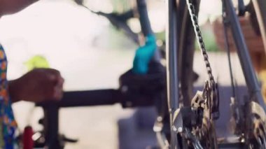 Bisiklet tekerleği zincirinin çok ırklı bir çift tarafından bakımını ve yağlanmasını yakından çek. Açık hava bisiklet etkinliği için bisiklet parçaları üzerinde kayganlaştırıcı kullanan iki elin görüntüsü.