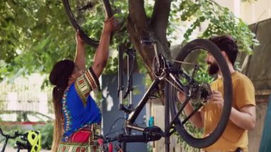 Özel ekipmanlarla bisiklet lastiklerini inceleyip sökmeye çalışan spor odaklı bir çift. Aktif adam kolu tamir ederken siyah kadın dışarıda bisiklet tekerleğini söker..