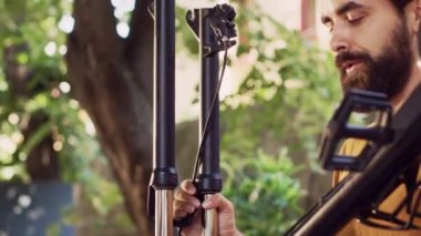 Dışarıdaki enerjik, ırklar arası çiftin yakın çekim görüntüleri. Bisiklet gövdesine güvenli bir şekilde tekerlek takıyorlar. Motosiklet lastiğinin detaylı görüntüsü genç sevgili ve kız arkadaş tarafından ayarlanıyor..