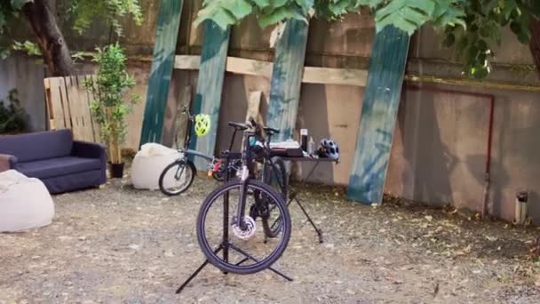 バックヤードの2台の自転車は 年間の夏の活動としてプロの機器との修理とメンテナンスを待っています 壊れた自転車は外で点検し 固定するために修理スタンドに置かれます — ストック動画