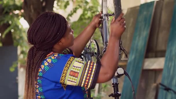 精力充沛的黑人妇女拆开损坏的自行车轮胎 以便修理和更换新轮胎 健康的非洲女运动员抓取并拆卸自行车轮作进一步维修之用 — 图库视频影像