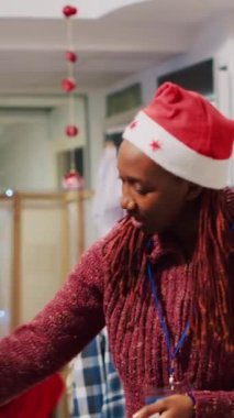 Bayram bayramında Noel Baba şapkası takan yardımsever dikey video perakendecisi en uygun spor ceket giyen ihtiyara yardım ediyor. Noel süslemeleri mağazasında çalışan yardımcı müşteri.