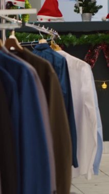 Noel süsleri mağazasında, kış tatili sezonunda hediye bekleyen müşterileri bekleyen resmi kıyafet gömleklerinin olduğu dikey video rafı. Xmas 'lı Blazerler moda butiğini süslüyor.
