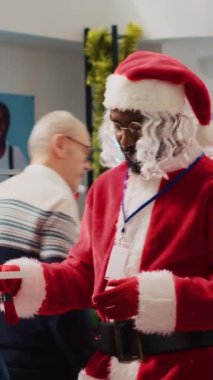 Noel Baba gibi giyinmiş dikey Afrikalı Amerikalı çalışanlar, kış tatili sezonunda Noel alışverişinde müşterilere şenlikli kıyafet seçmede yardımcı oluyorlar. Moda dükkanında müşteriye yardım eden işçi