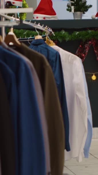 Vertikale Videoregale Mit Hemden Festlicher Kleidung Leerem Weihnachtlich Dekoriertem Bekleidungsgeschäft — Stockvideo