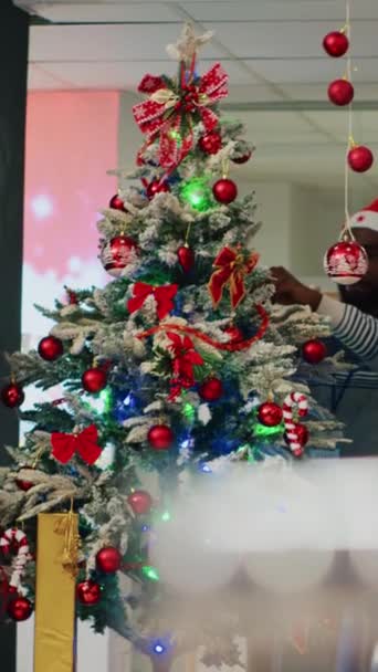 Függőleges Videó Afrikai Amerikai Alkalmazottak Viselnek Mikulás Kalap Díszítő Karácsonyfa — Stock videók