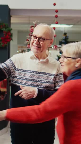 在圣诞前夕 一对老夫妇在圣诞节装饰购物中心的服装店里与孙子在网上视频聊天 让他在时髦的运动衫和礼物之间做出选择 — 图库视频影像