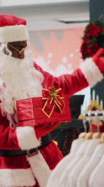 Noel Baba 'yı kostüm mağazasında taklit eden dikey video perakende asistanı müşterileri kış boyunca promosyon ödülü kazanmak için Noel çekilişine katılmaya davet ediyor.