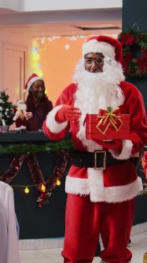 Noel Baba kostümü giyen bir adamın kış tatili sezonunda Noel süsleri mağazasında çekiliş yarışması düzenlerken çekilmiş dikey bir video.