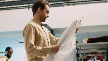 Genç müşteri raflardaki şık markalara bakıyor, alışveriş merkezlerinde indirimli moda kıyafetler alıyor. Perakende piyasasını kontrol eden kişi, küçük işletme. El kamerasıyla..