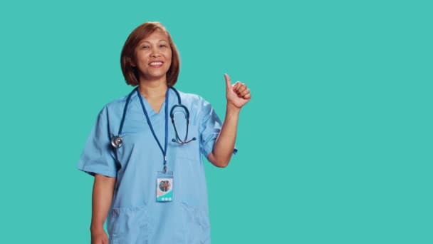 Gut Gelaunte Erfahrene Asiatische Krankenschwester Zeigt Bei Der Arbeit Isoliert — Stockvideo