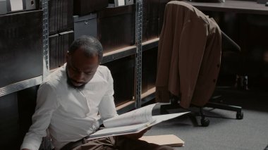 Soruşturmayı yürüten özel dedektif. Dava dosyaları ve gözetim fotoğraflarıyla çevrili. Kanun adamı sabıka kayıtlarını okuyor, bilgileri analiz ediyor..