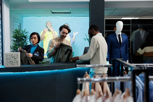 在商场时装店购物时 微笑着与顾客和出纳员在结帐时聊天 商店员工扫描服装并与非洲裔美国客户聊天 — 图库照片