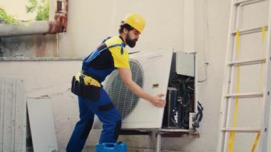 Hassas servis elemanı açık hava kliması arızası üzerinde çalışmaya başlıyor. Yoğunlaştırıcı ön bobin paneli sökülüyor. Hatalı kabloları kontrol etmek için harici hvac sistemini sökmekte usta bir uzman