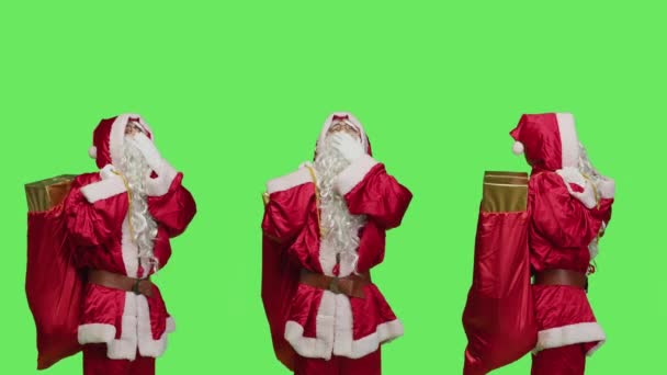 疲れた聖なるニッケルは緑色の背景 クリスマスのイブの休日のためのギフトやおもちゃで袋を運ぶことに疲れを感じます サンタクロースはスタジオで眠っている感じを体現します 赤いスーツ — ストック動画