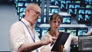 Yüksek teknolojili çalışma alanındaki organize yönetimler, dizüstü bilgisayardaki senaryoları çalıştırırken tablet üzerindeki görevleri tamamlıyorlar. Sunucu kümeleri arasında odaklanmış uzmanlar, veritabanlarına erişiliyor ve kodları değiştiriliyor