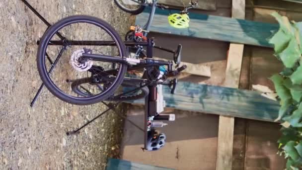 垂直ビデオ 裏庭の2台の自転車は 年間の夏の活動としてプロの機器との修理とメンテナンスを待っています 点検および固定のための修理スタンドに置かれた壊れた自転車 — ストック動画