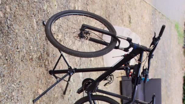 近代的な損傷した自転車の垂直ビデオビューは プロの機器とのメンテナンスの準備ができてホームヤードに配置され 固定されています 専用ツールボックス横の修理スタンドでの自転車の空中撮影 — ストック動画