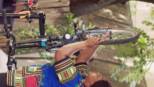 Вертикальне Відео Активна Афроамериканка Обережно Розпушується Знімає Пошкоджене Велосипедне Колесо — стокове відео