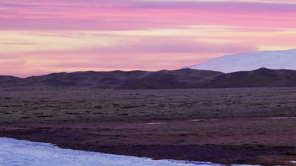 丘や雪の山とアイスランドの風景の中に美しいピンクの空 田舎の風光明媚なルート上の北欧のフィールド アイスランドの雄大な空と自然 手持ち撮影 — ストック写真