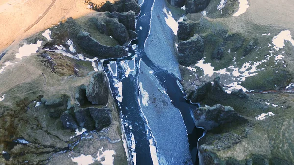 水の流れと美しい風景を形成する雪の山とアイスランドの峡谷のドローンショット アイスランドの川 自然の北極の景色を持つ壮大なフィヨルドのような峡谷 スローモーション — ストック写真