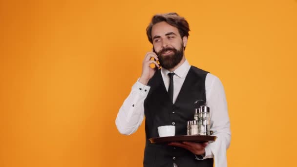 Étkezdében Pincér Telefonon Intézi Vacsoraidőpontokat Miközben Vendéglátóiparban Sárga Háttérrel Dolgozik — Stock videók
