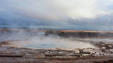 Reykjavik yakınlarındaki panoramik manzarada İzlanda gayzerleri, deliklerin püskürmesi ve sıcak su ve buharla güzel bir çeşme oluşturması. İzlanda 'da jeti ve manzarası olan İskandinav krateri. El kamerasıyla..