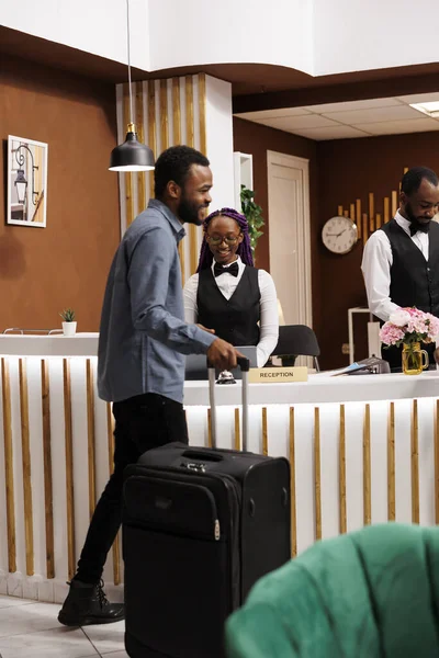 快乐的年轻的非裔美国人到达度假胜地 站在接待区登记入住酒店 享受极好的客户服务 在前台微笑的黑人游客 — 图库照片