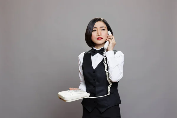 Młoda Pewna Siebie Azjatycka Kelnerka Mundurze Rozmawiająca Przez Telefon Stacjonarny — Zdjęcie stockowe