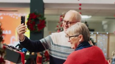 Neşeli yaşlı çift, Noel tatilinde mükemmel Noel hediyesi seçmek için tavsiye isterken online video görüşmesinde yeğeniyle sohbet etmek için akıllı telefon kullanıyor.